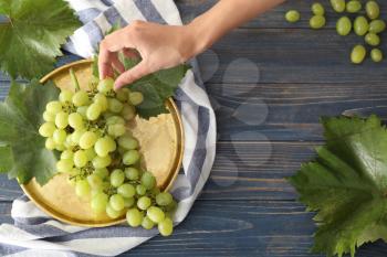 Woman taking ripe juicy grapes from metal tray�
