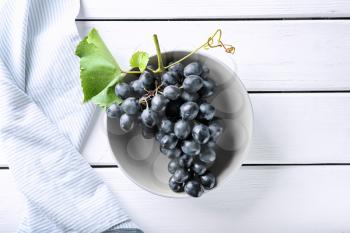 Plate with ripe sweet grapes on white wooden background�