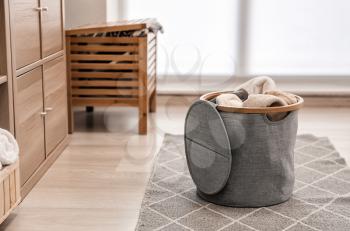 Laundry basket with dirty towels on floor in room�
