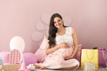 Beautiful pregnant woman with baby shower gifts at home�