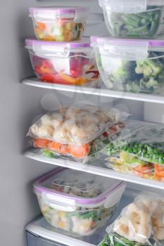 Containers and plastic bags with frozen vegetables in refrigerator�
