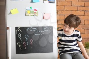 Little boy drawing on chalkboard in kitchen�
