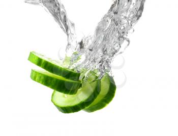 Falling of fresh cucumber slices into water against white background�