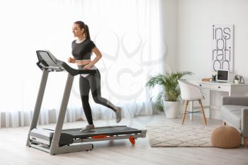 Sporty young woman training on treadmill at home�
