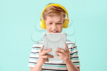 Cute little boy with tablet computer on color background. Concept of online education�