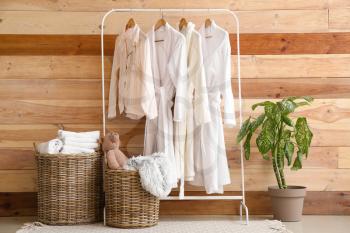 Baskets with laundry and clothes hanger near wooden wall in room�