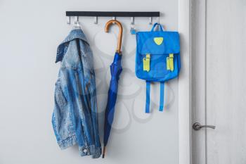 Umbrella with clothes and school backpack hanging on wall in hall�