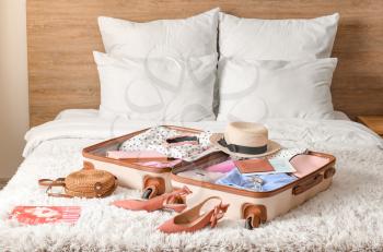 Suitcase with travel accessories on bed�