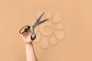 Female hand tailor's scissors on color background�