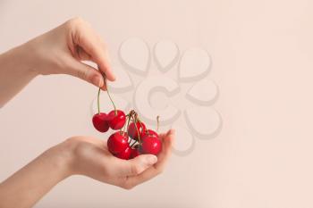 Female hands with sweet cherry on color background�