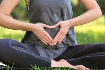 Young pregnant woman practicing yoga outdoors, closeup�