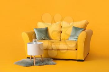 Stylish sofa and table on color background�