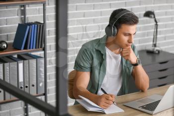 Man with headphones and laptop working in office�