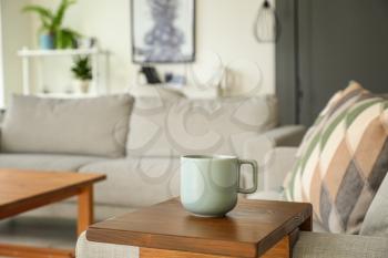 Cup of tea on armrest table in room�