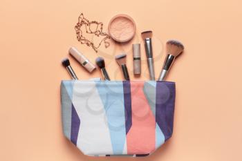 Bag with makeup cosmetics and accessories on color background�
