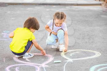 Little children drawing with chalk on asphalt�