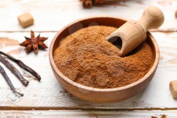 Bowl with cinnamon powder on wooden background�