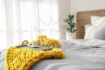 Knitted plaid with breakfast on bed at home�