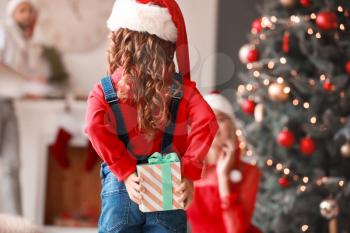 Cute girl hiding gift for her parents on Christmas eve�