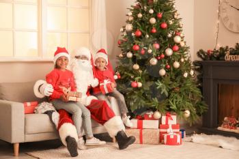 African-American Santa Claus with cute children at home on Christmas eve�