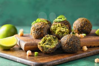 Board with tasty falafel balls and lime on color background�