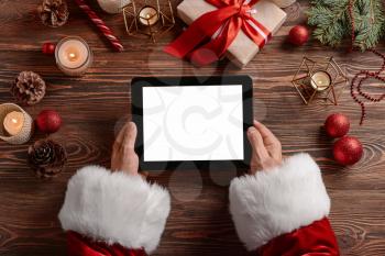 Santa Claus with tablet computer at table�