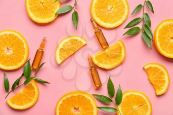 Ampules with vitamin C injection and orange fruit slices on color background�
