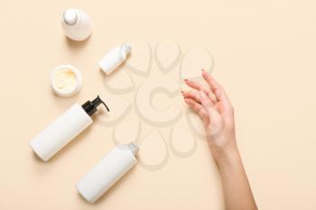 Female hand with cosmetic products on color background�