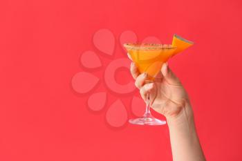 Female hand with glass of tasty pumpkin pie martini on color background�