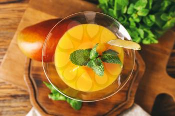 Glass of tasty mango margarita and ingredients on wooden background, closeup�