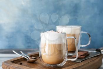 Glass cups of tasty latte on color background�
