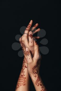 Beautiful female hands with henna tattoo on dark background�