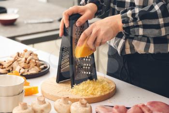Woman grating cheese in kitchen�