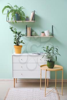 Interior of modern room with chest of drawers, table and shelves�