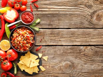 Bowls of tasty salsa sauces on wooden background�