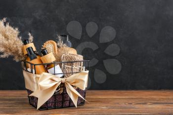 Gift basket with cosmetic products on dark wooden background�