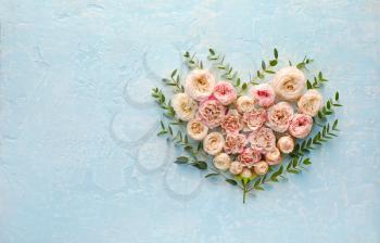 Heart made of beautiful flowers on color background�