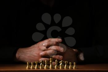 Man playing chess on dark background, closeup 