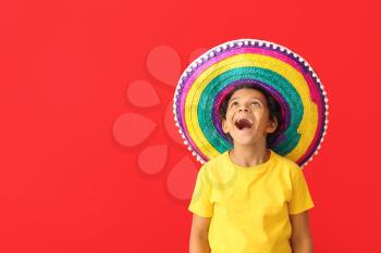 Funny Mexican boy in sombrero hat on color background�