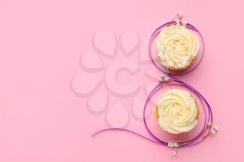 Figure 8 made of violet ribbon and cupcakes on color background. International Women's Day celebration�