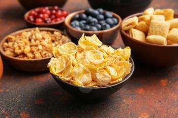 Bowls with different cereals and berries on grunge background, closeup�