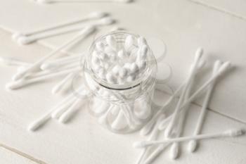 Jar with cotton swabs on light background�