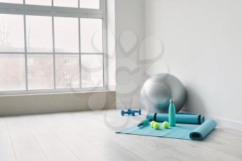 Set of sports equipment with fitness ball near light wall�
