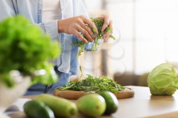 Young woman cooking fresh salad in kitchen�
