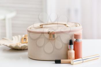 Stylish bag with decorative cosmetics on table in room�