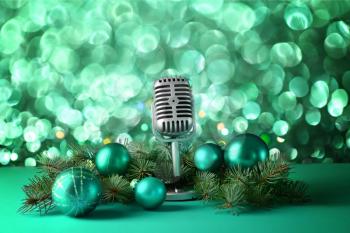 Retro microphone with Christmas decor on table against blurred lights�