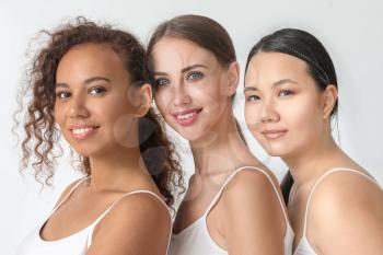 Portrait of beautiful young women with different tones of skin on light background�