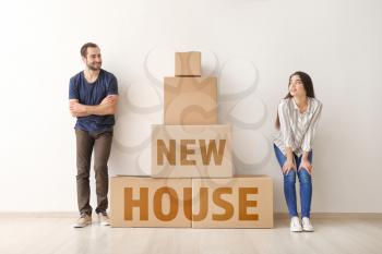 Young couple near boxes indoors. Moving into new house�