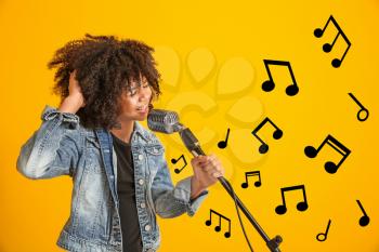 African-American girl with microphone singing against color background�