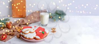 Plate with tasty Christmas cookies and glass of milk on table�